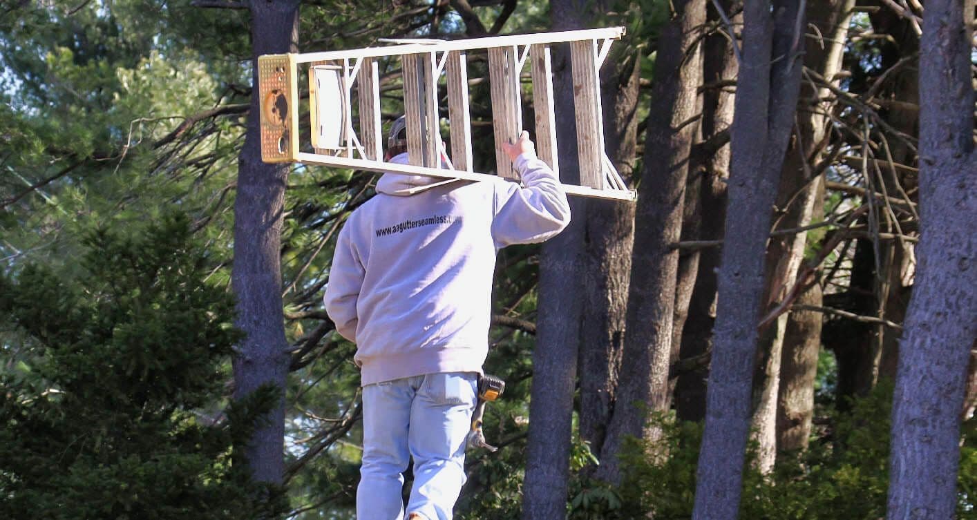A&A worker carrying ladder through wooded property