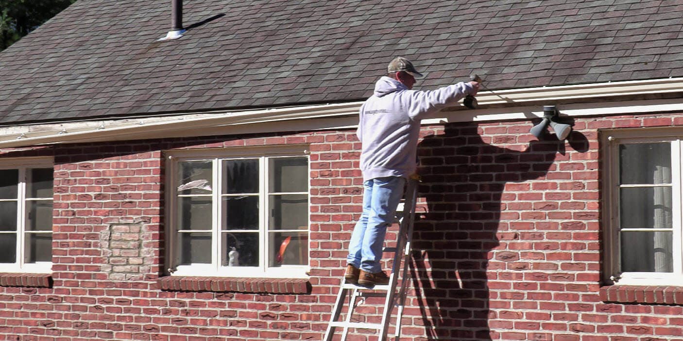 Wide shot of gutter installation on brick house